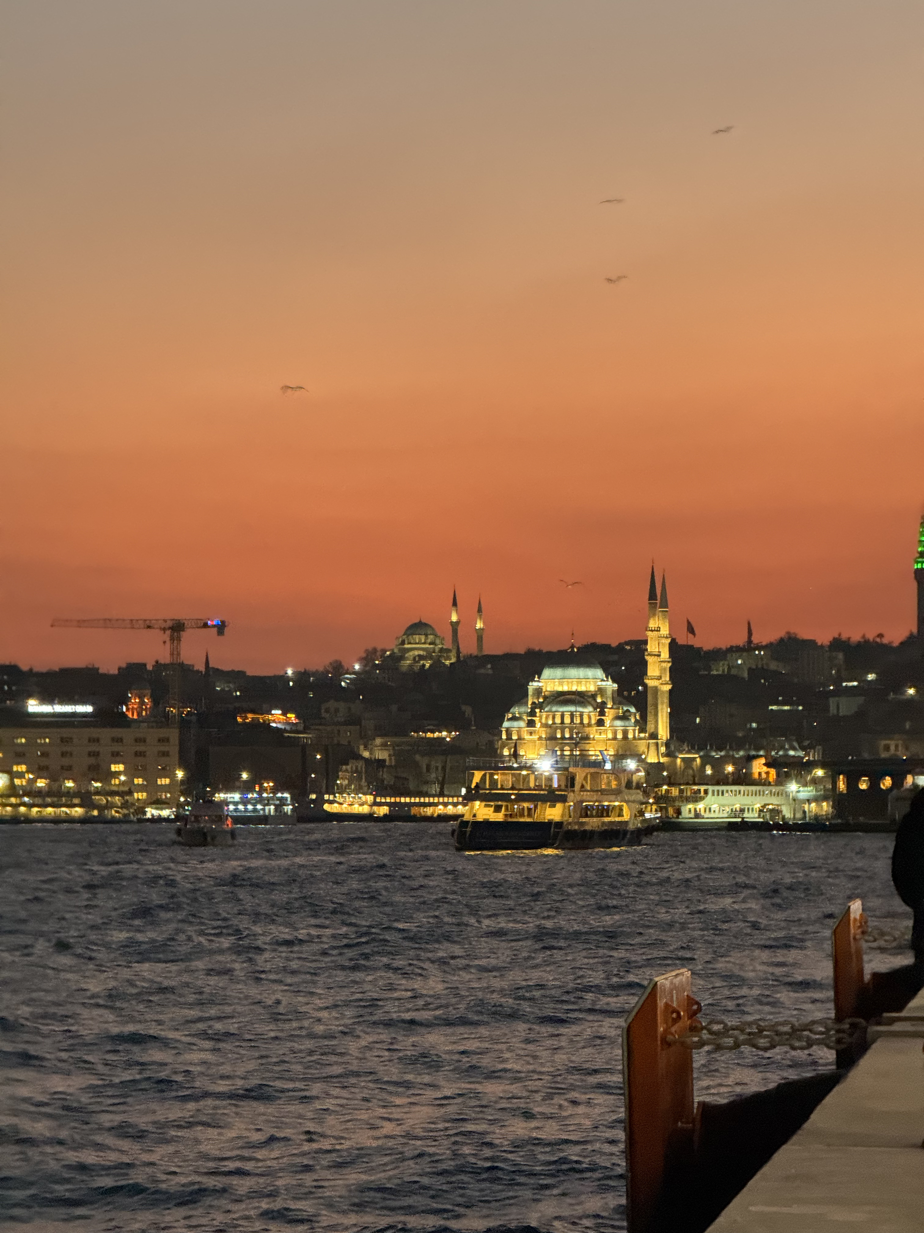 Geceleyin kıpkırmızı bir gökyüzü altında İstanbul Boğazı ve bir cami